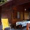 Una veranda in legno con lettino giallo e tavolo coperto da tovaglia con limoni.