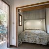 Stanza con letto matrimoniale, lenzuola a motivi blu, e porta a vetri con tenda a fili.