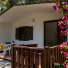 Veranda con staccionata di legno, fioritura rosa e mobili da giardino bianchi.