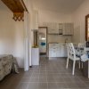 Interno di una cucina con tavolo, sedie e una finestra luminosa.