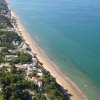 Vista aerea di una costa con spiaggia e edifici verdi.