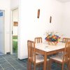 Sala da pranzo con tavolo, sedie e fiori. Porta aperta su bagno blu.