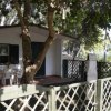 Una piccola casa bianca con patio, circondata da una staccionata e alberi.