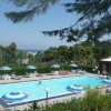 Piscina all'aperto circondata da ombrelloni e sedie a sdraio, con vista sul mare.