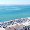 Vista aerea di una spiaggia con ombrelloni blu e bagnanti nel mare.