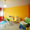 Stanza colorata con pareti gialle e rosse, sedie colorate, tavolino e seggioloni per bambini.
