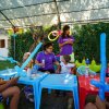 Bambini sotto un tendone giocano con educatori usando palloncini modellabili.