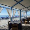 Tavolo apparecchiato su una terrazza vista mare con tende bianche.