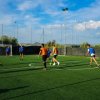 Persone giocano una partita di calcetto su un campo in erba sintetica all'aperto.