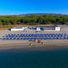 Spiaggia con ombrelloni blu e un edificio bianco, vista dall'alto.