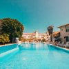 Piscina all'aperto con lettini e ombrelloni, circondata da edifici.