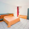 Camera con letto matrimoniale arancione, letto singolo, armadio verde, tende rosse.
