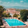 Piscina all'aperto circondata da palme e lettini, vista panoramica.