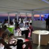 Lounge bar in spiaggia con tavoli luminosi e persone sedute al tramonto.