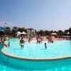 Persone in una piscina con aree ludiche e palme attorno.