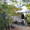 Una zona pranzo all'aperto con tavolo e sedie bianche sotto un gazebo tra alberi e arbusti.
