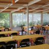 Una sala da pranzo con tovaglie gialle e sedie nere, circondata da finestre.
