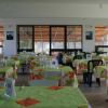Un'ampia sala da pranzo con tovaglie verdi e motivi floreali, tavoli numerati.