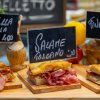 Tre panini con diversi tipi di salumi italiani esposti su un tavolo di legno.
