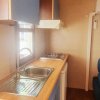 Cucina compatta con lavello, fornello, e mobili blu, all'interno di una casa mobile.
