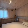 Camera da letto in legno chiaro con letto matrimoniale, finestra con tenda bianca e lampada appesa.