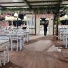 Un ristorante con tavoli e sedie bianche, decorato con piante e luci appese.