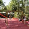 Parco giochi con scivolo, altalene e bambini che giocano.