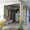 Interno di una veranda con tavolo, sedie, fiori, e cucina visibile sullo sfondo.