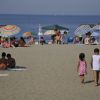 Una spiaggia affollata con persone sotto ombrelloni colorati vicino al mare.