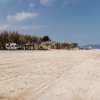 Spiaggia deserta con caravan e alberi.